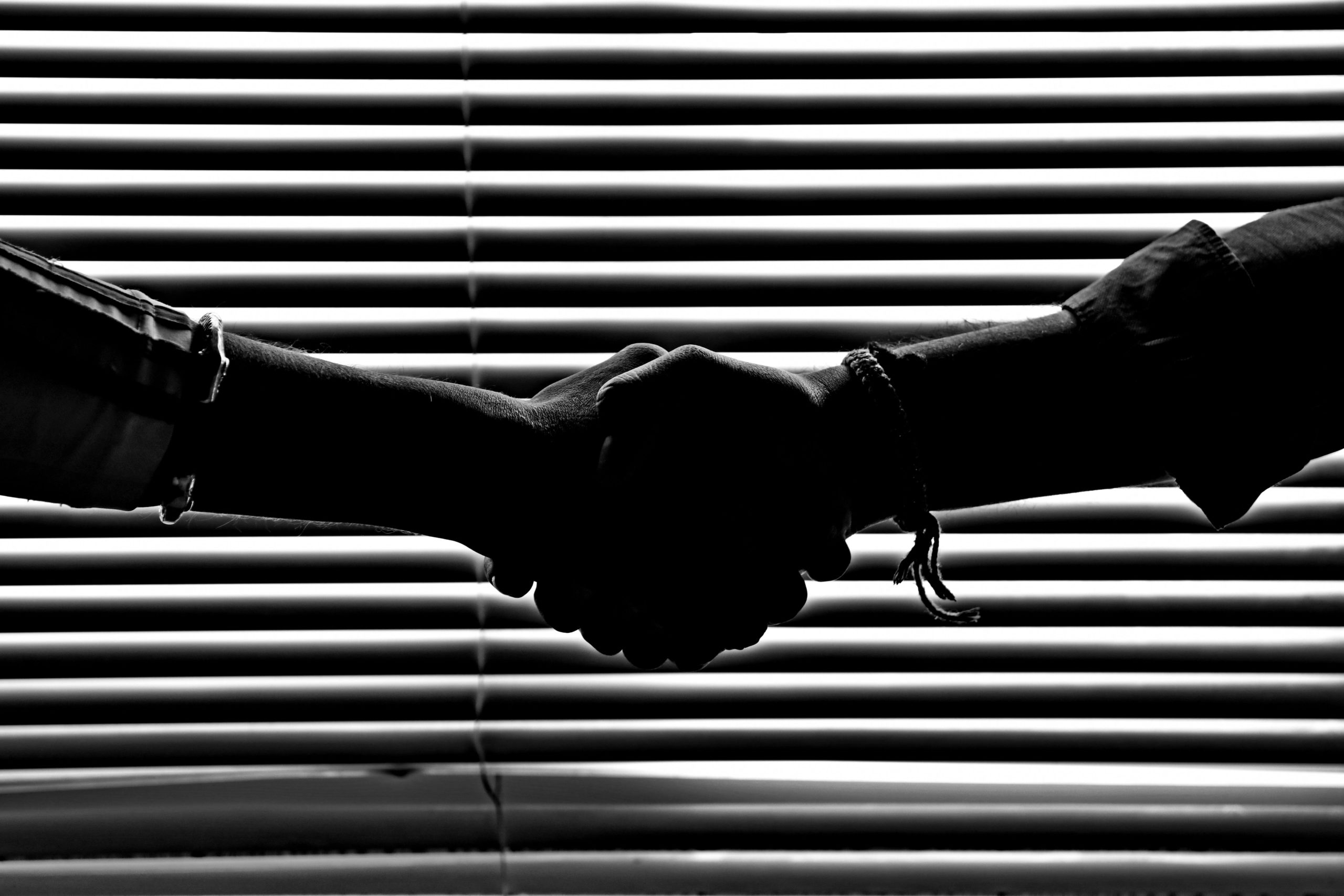 Home Silhouette of two people shaking hands symbolizing partnership and trust.
